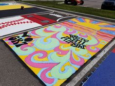 colorful street art painted on the side of a road with cars parked in the background