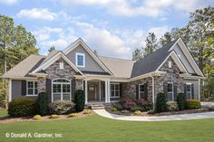 a house that is in the middle of some grass and trees with bushes around it