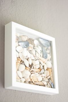 there is a white frame with seashells in it on the wall next to a light switch