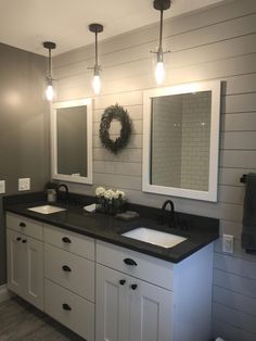 a bathroom with two sinks, mirrors and lights on the wall next to each other