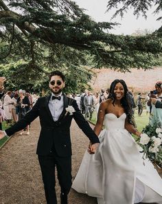 a bride and groom holding hands while walking down a path with confetti in hand