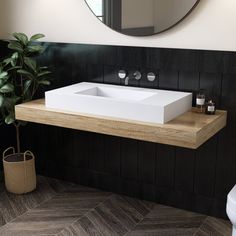 a white sink sitting on top of a wooden counter next to a potted plant