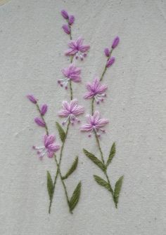 some pink flowers are embroidered onto a white piece of cloth