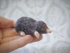 someone holding a tiny toy animal in their left hand and it looks like they are made out of wool