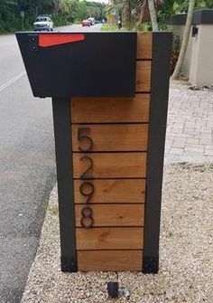 a mailbox sitting on the side of a road next to a tree and bushes