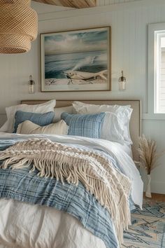 a bed with blue and white linens in a bedroom next to a painting on the wall