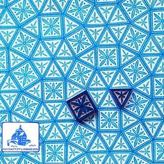 two blue dices sitting on top of a white and blue wallpaper with geometric designs