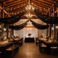 the inside of a barn decorated for a wedding with lights and chandeliers hanging from the ceiling