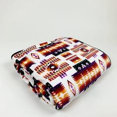 a multicolored blanket is folded up on a white surface with an orange and purple pattern