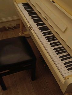 a piano sitting on top of a hard wood floor next to a chair and stool