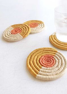 three coasters with different colors and designs on them next to a glass of water