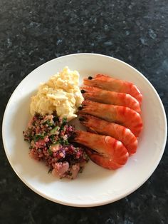 a plate with shrimp, mashed potatoes and other food items on it sitting on a table