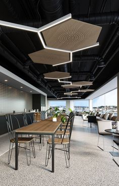 an office with tables, chairs and couches in it's center area is lit by recessed lights