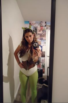 a woman taking a selfie in front of a mirror wearing green leggings