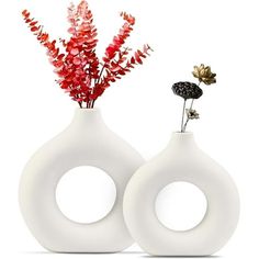 two white vases with flowers in them sitting side by side on a white surface