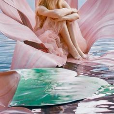 a woman sitting on top of a pink flower floating in the water with her arms crossed