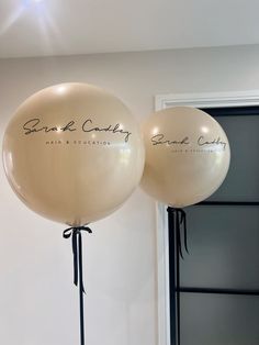 two white balloons with black writing on them