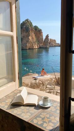 an open book sitting on top of a table next to a cup and saucer