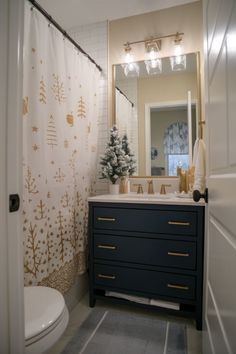 a bathroom with a christmas tree on the counter and shower curtain in the mirror above it