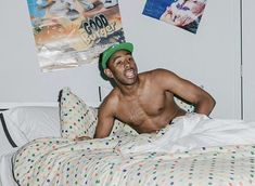 a shirtless man laying on top of a bed with polka dot sheets and pillows