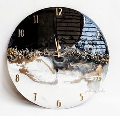 a white clock with black and gold designs on it's face that reads twelve o'clock