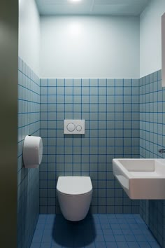 a blue tiled bathroom with a toilet and sink