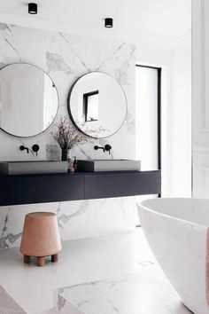 a bathroom with two round mirrors on the wall and a bathtub next to it