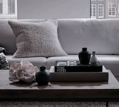 a coffee table with two vases on top of it in front of a couch