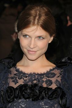 a woman with blue eyes wearing a black dress and posing for the camera at an event