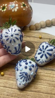 someone is holding three chocolate covered strawberries on a wooden board next to a potted plant