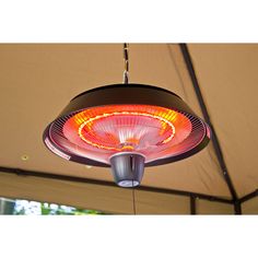 an electric heater hanging from the ceiling in a tent with trees in the background