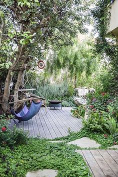 a hammock in the middle of a garden with trees and plants around it