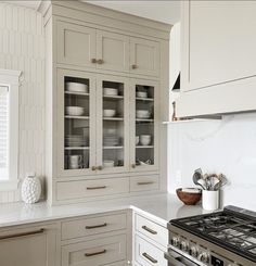 a kitchen with white cabinets and marble counter tops, including a stove top oven in the center