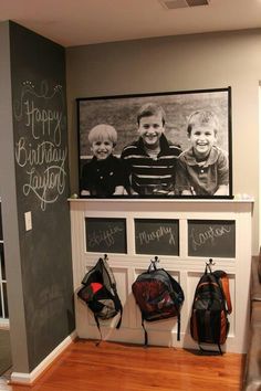 two children's backpacks are hanging on the wall next to a chalkboard