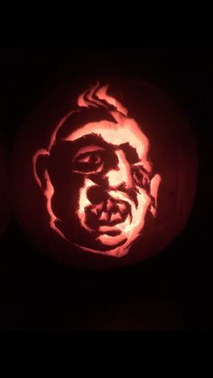 a pumpkin carved to look like a man's face is lit up in the dark