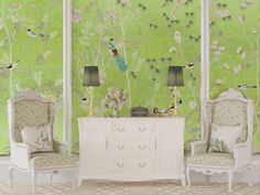 two white chairs sitting next to each other in front of a green wall with birds on it