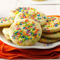 a plate full of cookies with sprinkles on it and an orange napkin