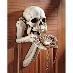 a skeleton holding a pocket watch in its hand on a wooden door with a chain hanging from it's side