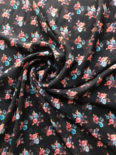 a black floral print fabric with pink and blue flowers