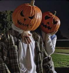 two people with pumpkins on their heads, one is holding the other's head