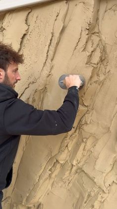 a man is painting the side of a wall with paint rollers and sand on it