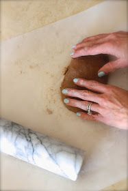 a woman is rolling out dough on a counter with a rolling stone next to her