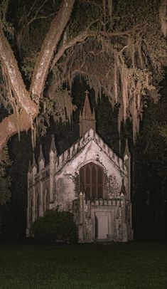 an old church with moss hanging from the trees