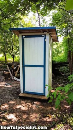 a white and blue outhouse in the woods