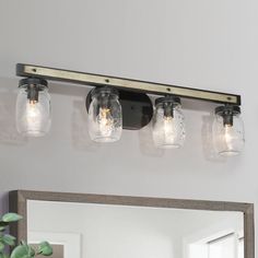 three mason jar lights are hanging on the wall above a vanity mirror and light fixture