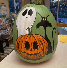 a pumpkin decorated to look like jack - o'- lantern with ghost and cat on it