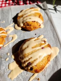 two scones covered in icing sitting on top of a baking sheet