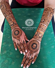 two hands with henna tattoos on them, one is showing off the intricate design