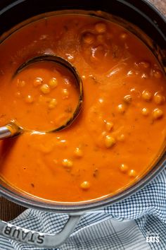 a ladle in a pot filled with beans and garnish on top of a table