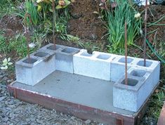 cement blocks are placed in the ground to form a planter for flowers and plants